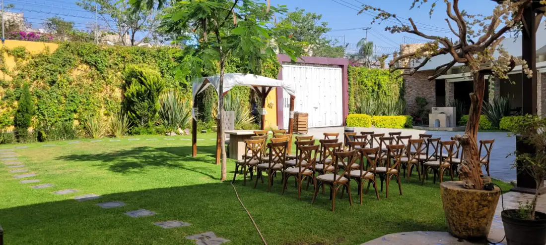 Camino de piedra del jardín hacia el gazebo blanco de la ceremonia, con sillas crossback a los lados