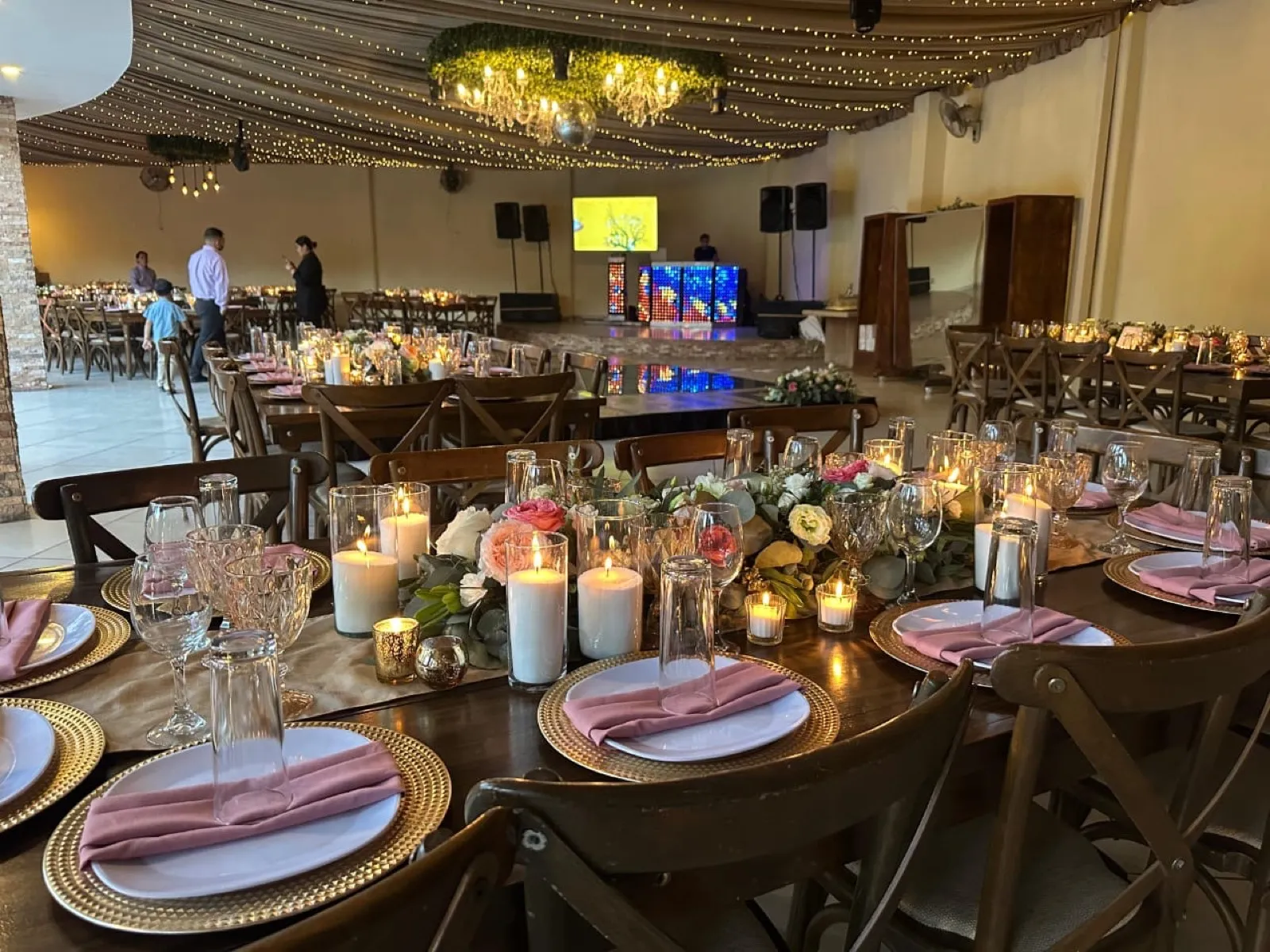 Salón de Bonanza de día con mesas montadas, velas, flores y servilletas rosas bajo el cielo de luces